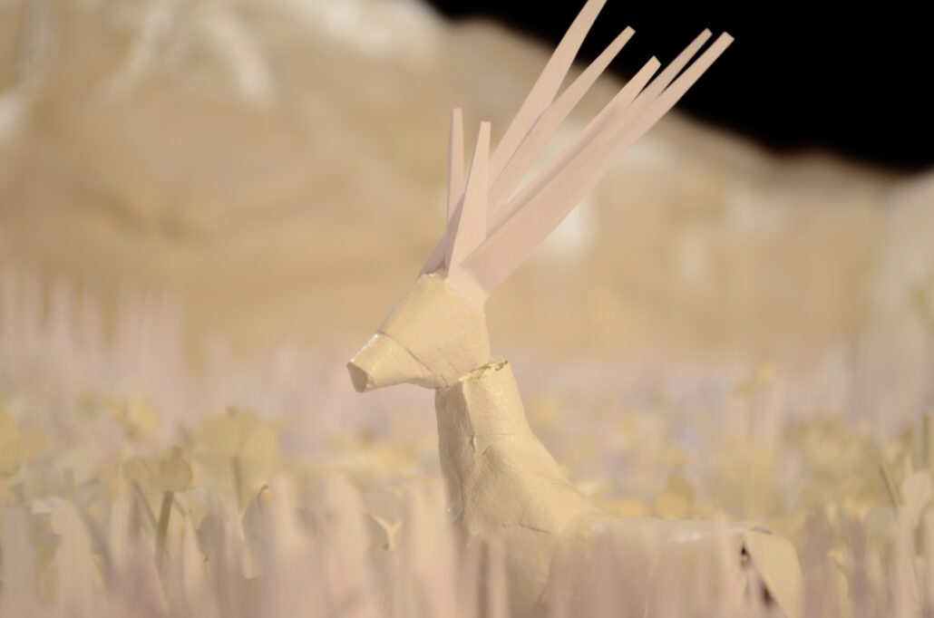 Weisser Papierhirsch steht auf einer Wiese aus weissen Papiergras